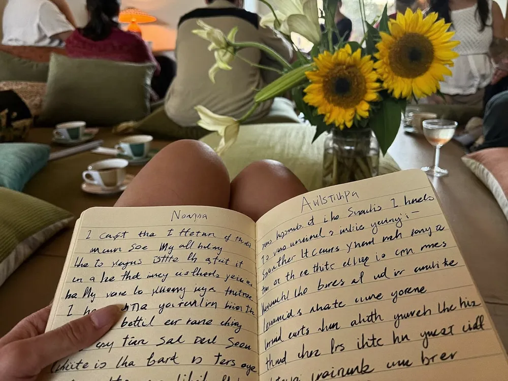 A notebook of poetry open on a cushion in warm lamplight